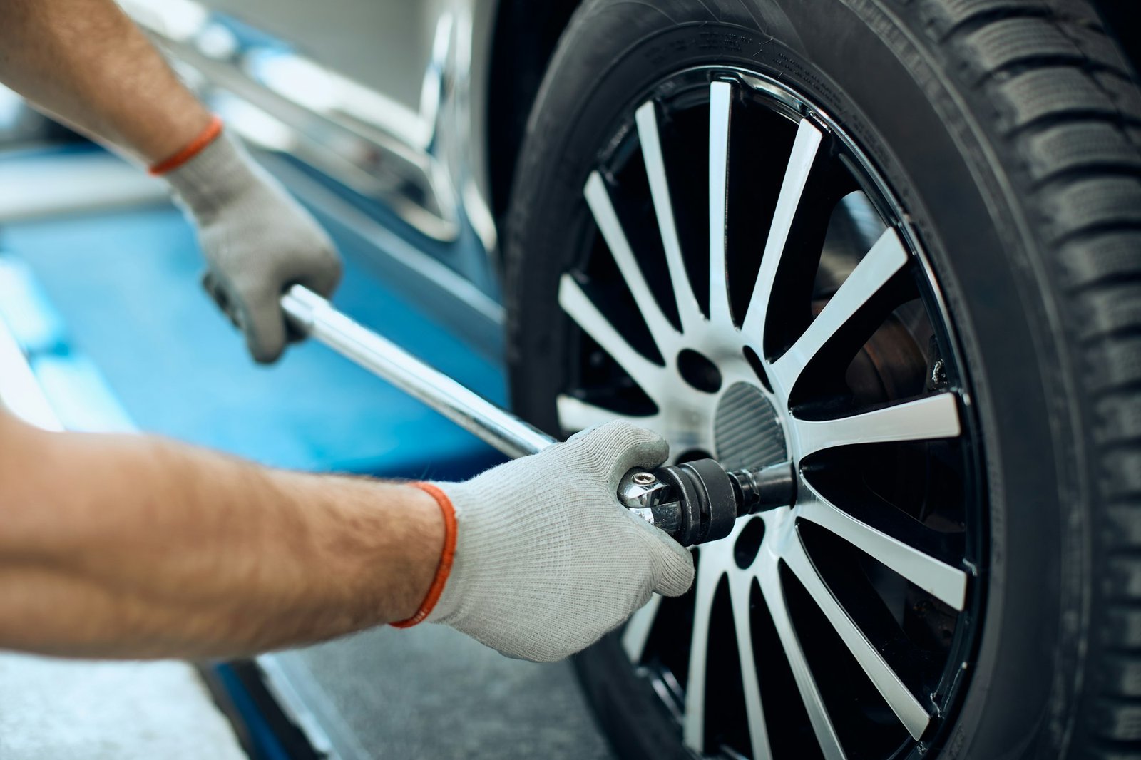 Close-up of repairman changing tire at car service workshop.